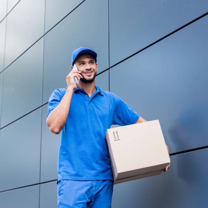 smiling-delivery-man-with-cardboard-box-talking-by-KRPQTTS.jpg